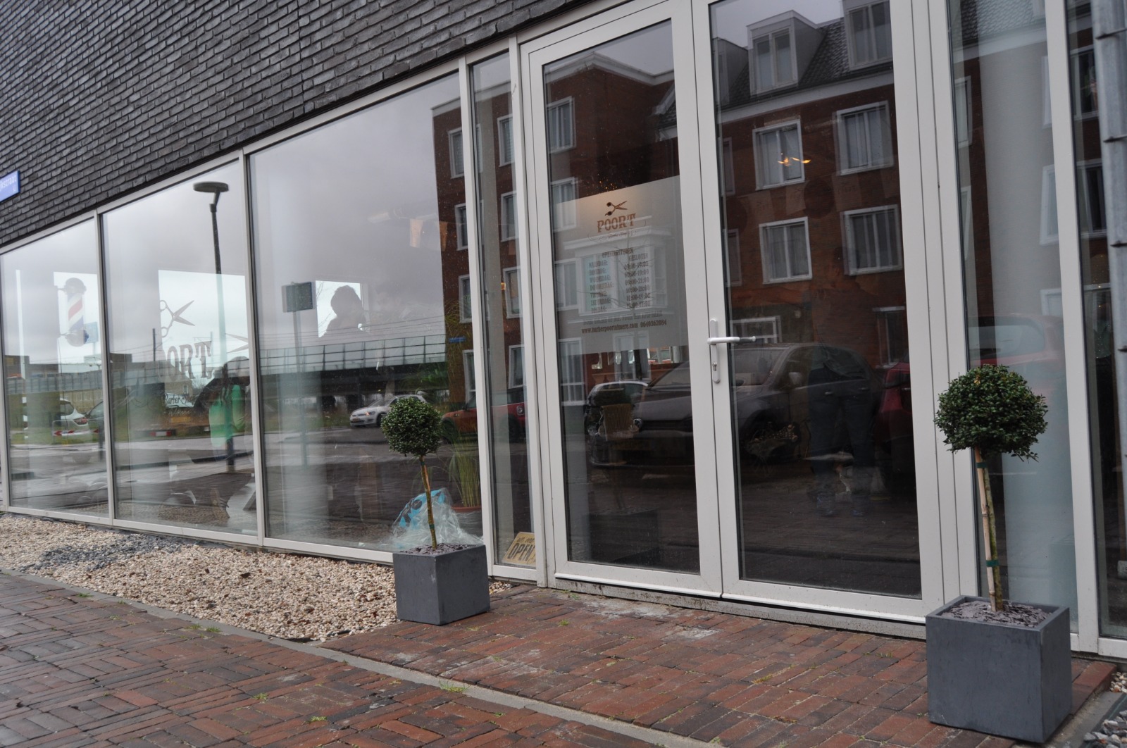 Buitenkant van Barber Poort Almere overdag met barberpaal