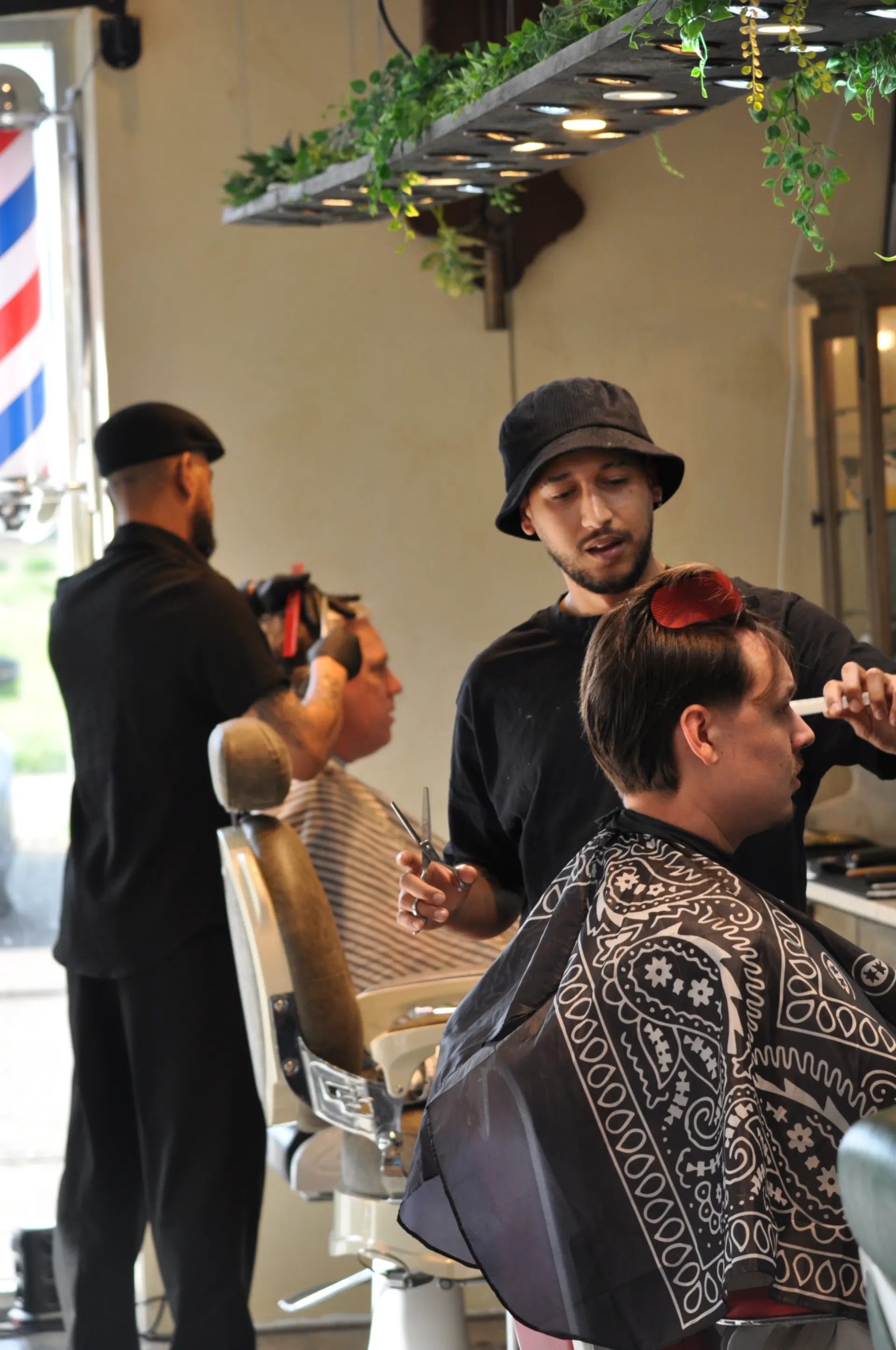 Twee barbers knippen klanten naast elkaar in Barber Poort Almere